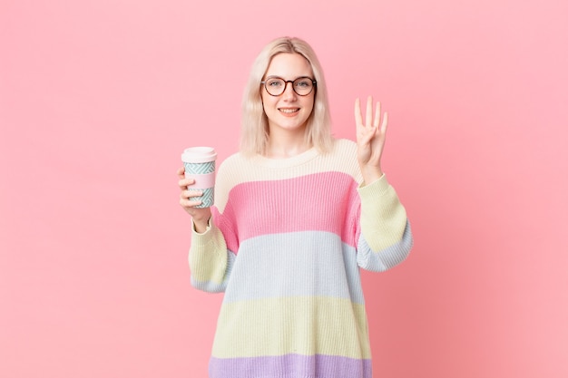 Mujer bonita rubia sonriendo y mirando amigable, mostrando el número cuatro. concepto de cafe