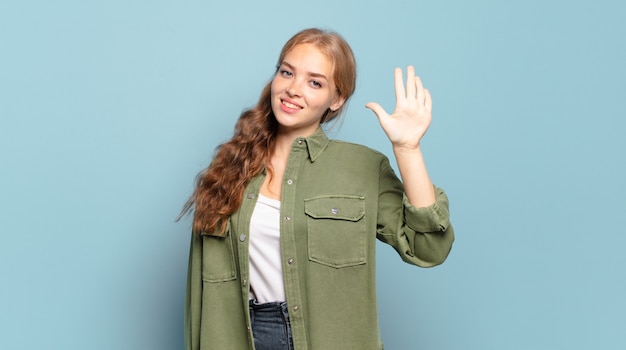 Mujer bonita rubia sonriendo y mirando amistosamente, mostrando el número cinco o quinto con la mano hacia adelante, contando hacia atrás