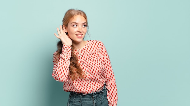 mujer bonita rubia sonriendo, mirando con curiosidad hacia un lado, tratando de escuchar chismes o escuchar un secreto