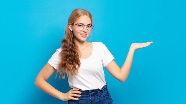 Mujer bonita rubia sonriendo, sintiéndose confiada, exitosa y feliz, mostrando el concepto o la idea en el espacio de la copia en el lateral