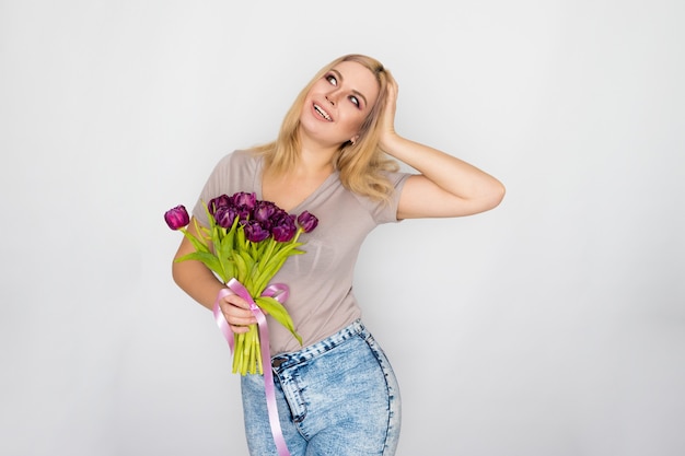 Mujer bonita rubia sosteniendo tulipanes púrpuras en sus manos