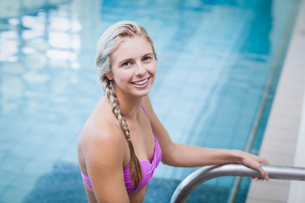 Mujer bonita saliendo del agua en la piscina