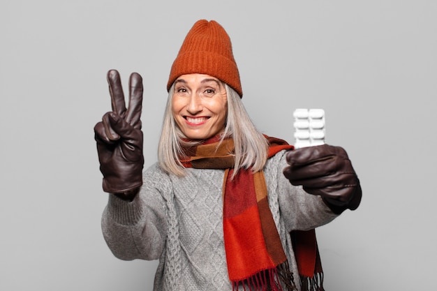 Mujer bonita senior con una tableta de píldoras vistiendo ropa de invierno