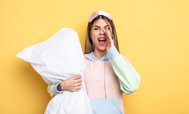 Mujer bonita sintiéndose feliz dando un gran grito con las manos al lado del concepto de pijama de boca