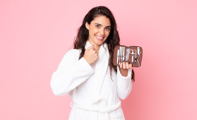 Mujer bonita sintiéndose feliz y enfrentando un desafío o celebrando y sosteniendo una bolsa de maquillaje con herramientas de uñas