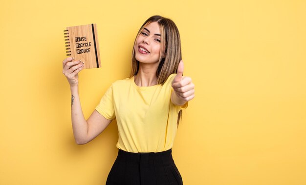 mujer bonita sintiéndose orgullosa, sonriendo positivamente con los pulgares hacia arriba. concepto de reciclaje