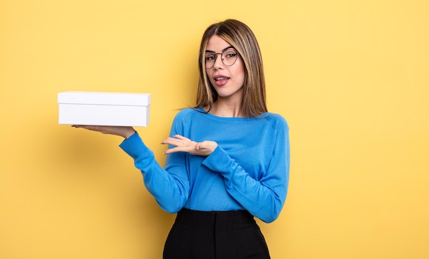 mujer bonita sonriendo alegremente, sintiéndose feliz y mostrando un concepto. sosteniendo caja blanca