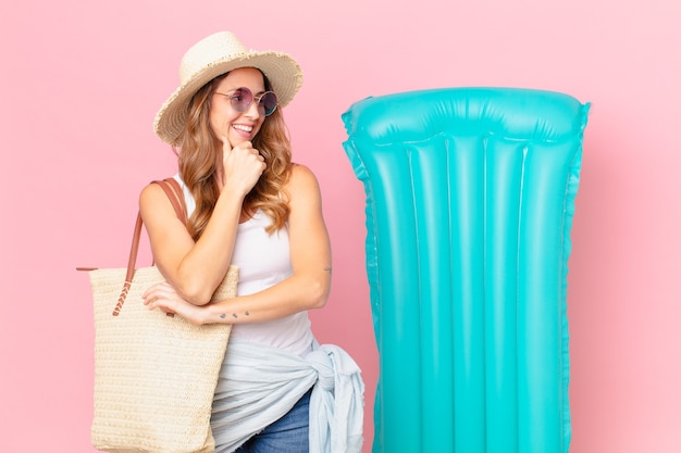 Mujer bonita sonriendo con una expresión feliz y segura con la mano en la barbilla. concepto de verano