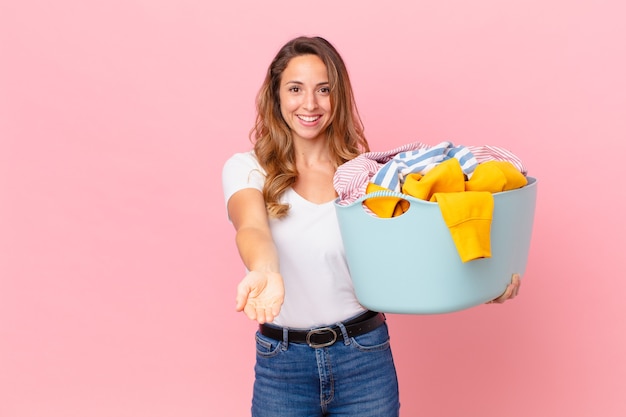 Mujer bonita sonriendo felizmente con amable y ofreciendo y mostrando un concepto y lavando ropa.