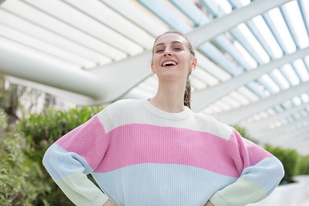 Mujer bonita sonriendo felizmente con las manos en la cadera y una actitud segura, orgullosa y amistosa.