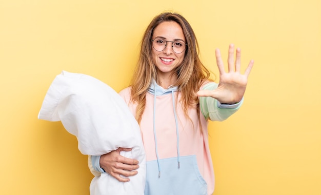 Mujer bonita sonriendo y luciendo amigable mostrando el concepto de pijama número cinco