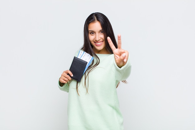 Foto mujer bonita sonriendo y luciendo feliz, despreocupada y positiva, gesticulando victoria o paz con una mano