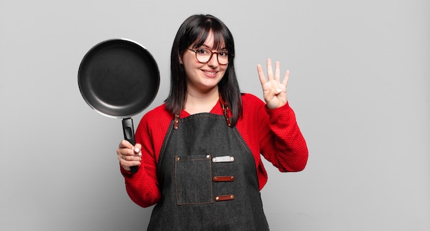 Mujer bonita sonriendo y mirando amistosamente, mostrando el número cuatro o cuarto con la mano hacia adelante, contando hacia atrás