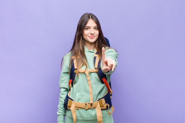 Mujer bonita sonriendo con orgullo y confianza haciendo la pose número uno triunfalmente, sintiéndose como una líder