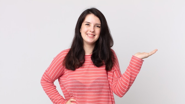 Mujer bonita sonriendo, sintiéndose confiada, exitosa y feliz, mostrando el concepto o la idea en el espacio de la copia en el lateral