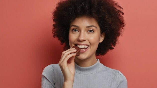 Una mujer bonita y sonriente come el dulce chocolate negro en un blanco