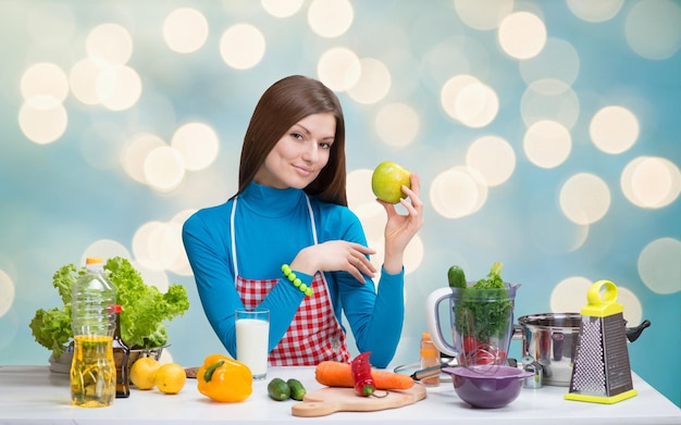 Mujer bonita sonriente con manzana verde en la cocina