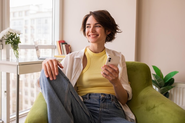 Mujer bonita sonriente mirando a otro lado con el teléfono