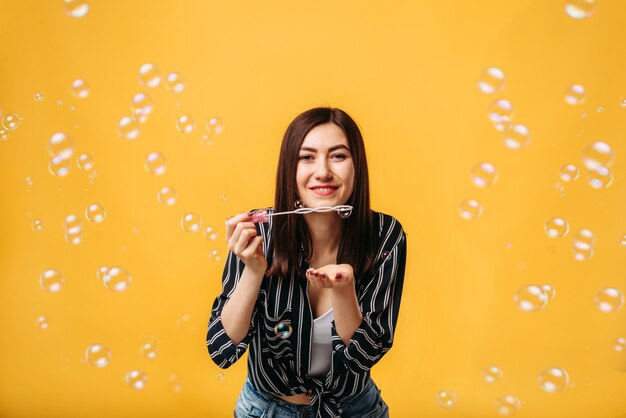 Mujer bonita sopla en pompas de jabón