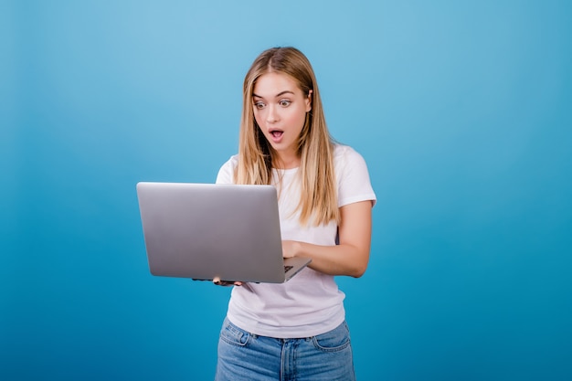 Mujer bonita sorprendida con laptop en azul