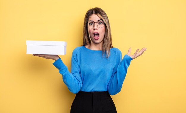 Mujer bonita sorprendida sorprendida y asombrada con una sorpresa increíble sosteniendo una caja blanca