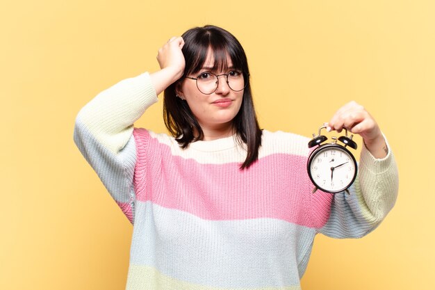 Mujer bonita de talla grande con un reloj despertador