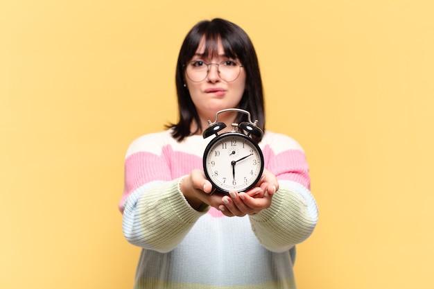 Mujer bonita de talla grande con un reloj despertador