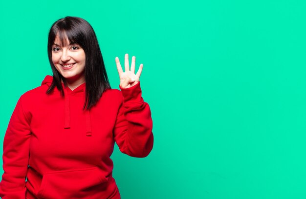 Mujer bonita de talla grande sonriendo y mirando amigable, mostrando el número cuatro o cuarto con la mano hacia adelante, contando hacia atrás