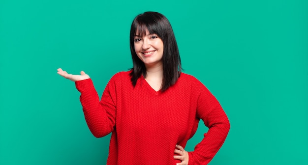 Mujer bonita de talla grande sonriendo, sintiéndose segura, exitosa y feliz, mostrando el concepto o la idea en el espacio de la copia en el lateral