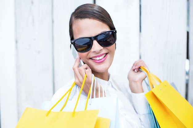 Mujer bonita en el teléfono con bolsas de compras