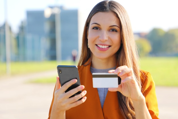 Mujer bonita con un teléfono inteligente y una tarjeta de crédito