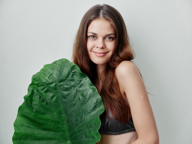 Mujer bonita en traje de baño hoja verde encanto exótico fondo claro