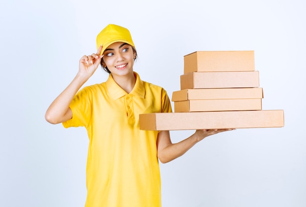 Una mujer bonita en uniforme amarillo con cajas de papel artesanal marrón en blanco.