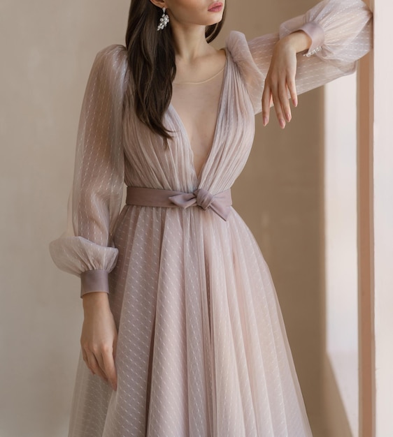 Foto mujer bonita vestida con un precioso vestido de manga larga con escote precioso vestido de manga larga decorado con cinturón y lazo