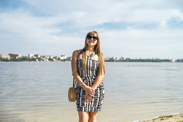 Mujer bonita en vestido cerca del lago, horario de verano