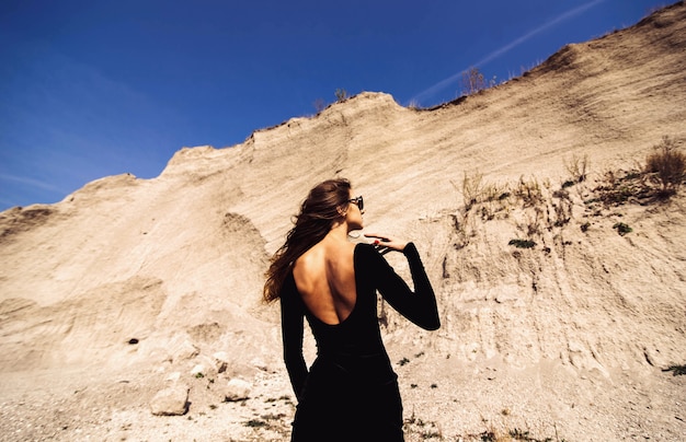 Mujer bonita en vestido largo negro caminando al aire libre