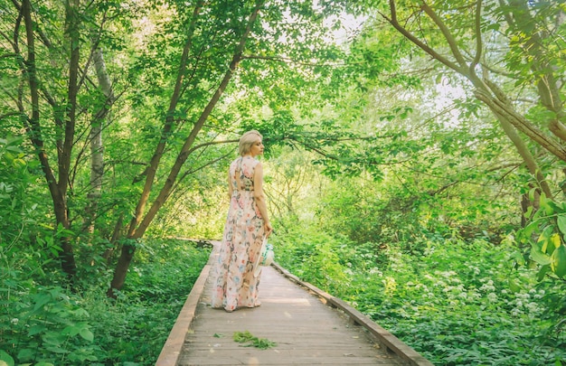 Mujer bonita en vestido largo en temporada de verano en el parque.