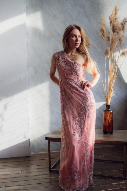 Mujer bonita en vestido de noche con peinado posando cerca de un bar restaurante mirando a la cámara