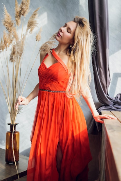 Mujer bonita en vestido de noche con peinado posando cerca de un bar restaurante mirando a la cámara