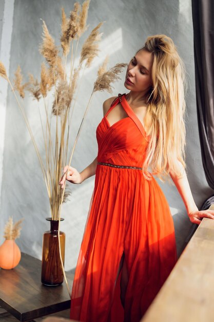 Mujer bonita en vestido de noche con peinado posando cerca de un bar restaurante mirando a la cámara