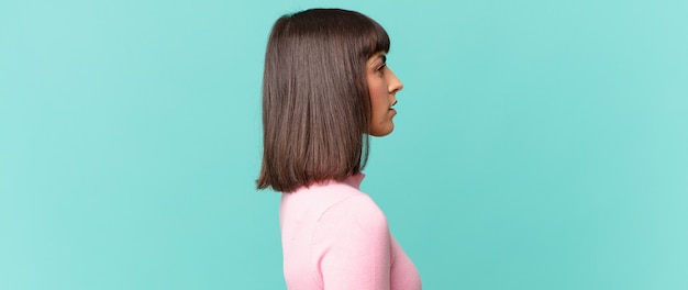 Mujer bonita en vista de perfil mirando para copiar el espacio por delante, pensando, imaginando o soñando despierto