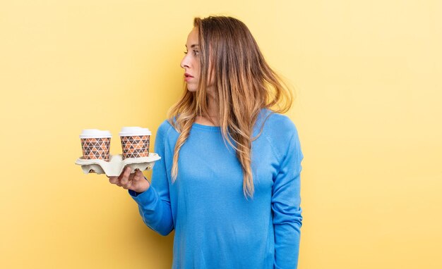 Mujer bonita en vista de perfil pensando, imaginando o soñando despierta. concepto de café para llevar