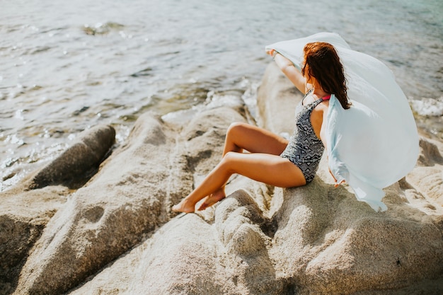 Mujer bonita yung en la playa pedregosa junto al mar