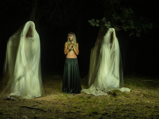 Foto mujer en el bosque entre dos fantasmas mirándola