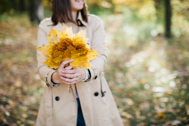 Mujer en el bosque de otoño con hojas en sus manos La mujer es feliz