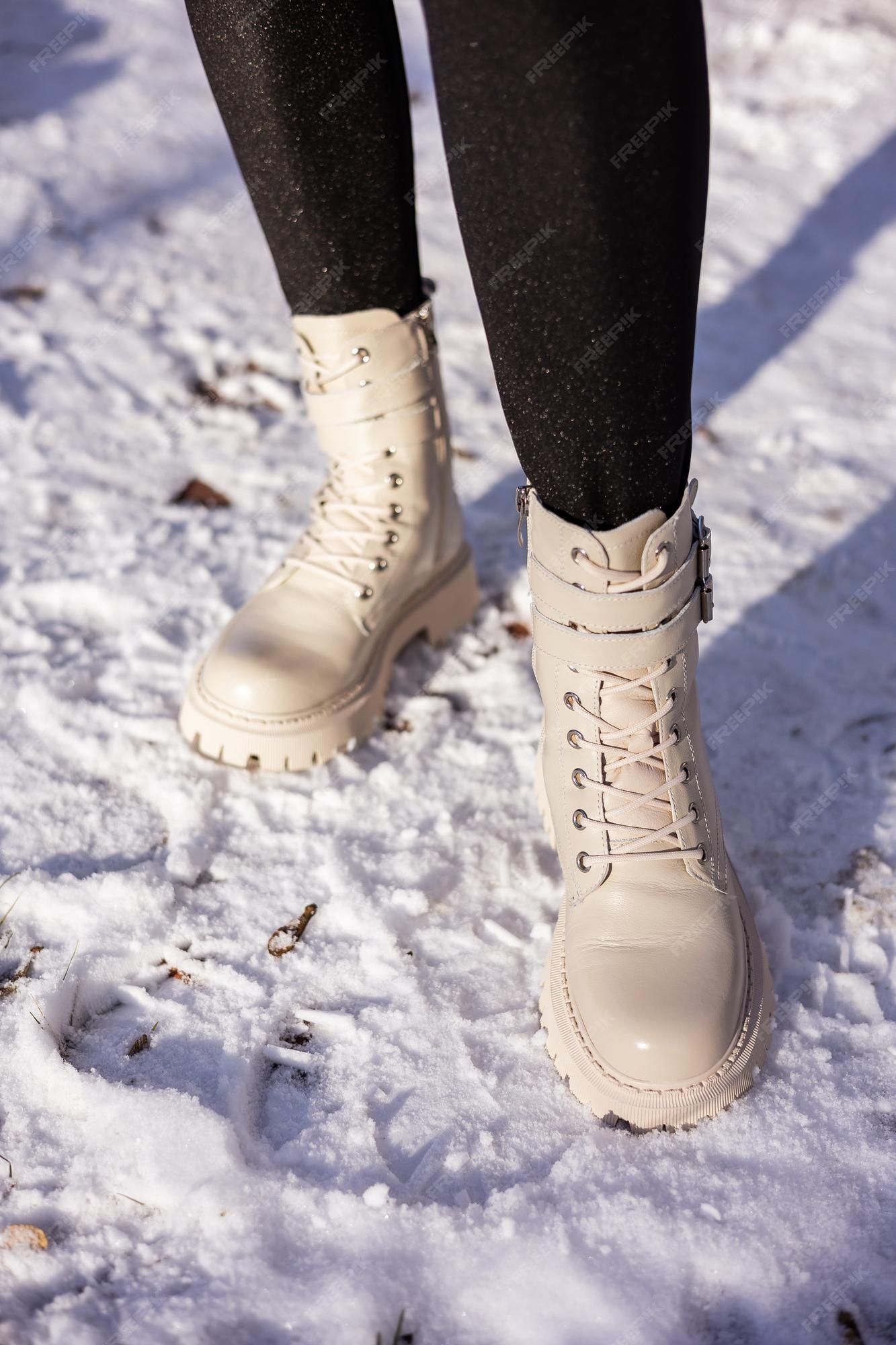 Mujer en botas de moda en primer plano de nieve blanca | Premium