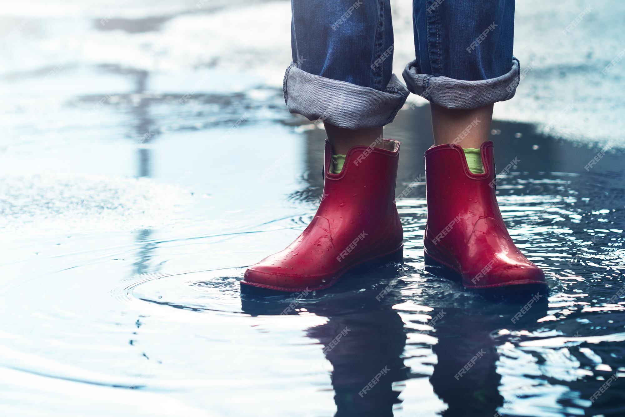 Mujer con botas cortas rojas de pie un charco de lluvia Foto Premium