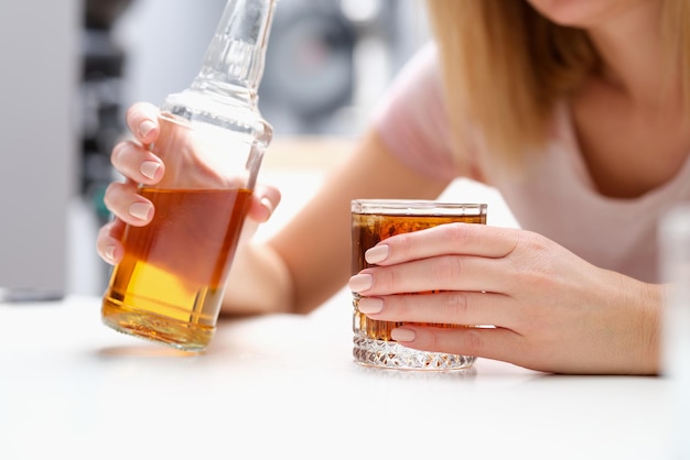 Foto mujer con botella de alcohol y vidrio sola.