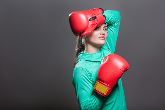 Mujer boxeadora con ropa deportiva verde y guantes de boxeo rojos