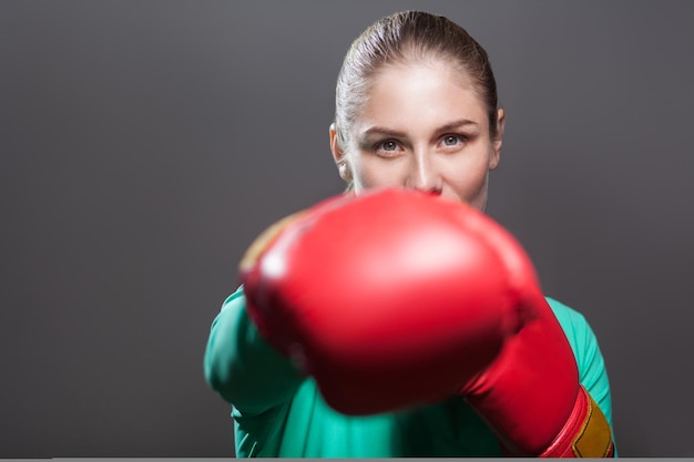 Mujer de boxeo en ropa deportiva verde y guantes de boxeo rojos